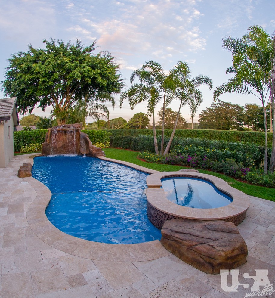 Example of a large tuscan backyard stone and kidney-shaped aboveground pool fountain design in Miami