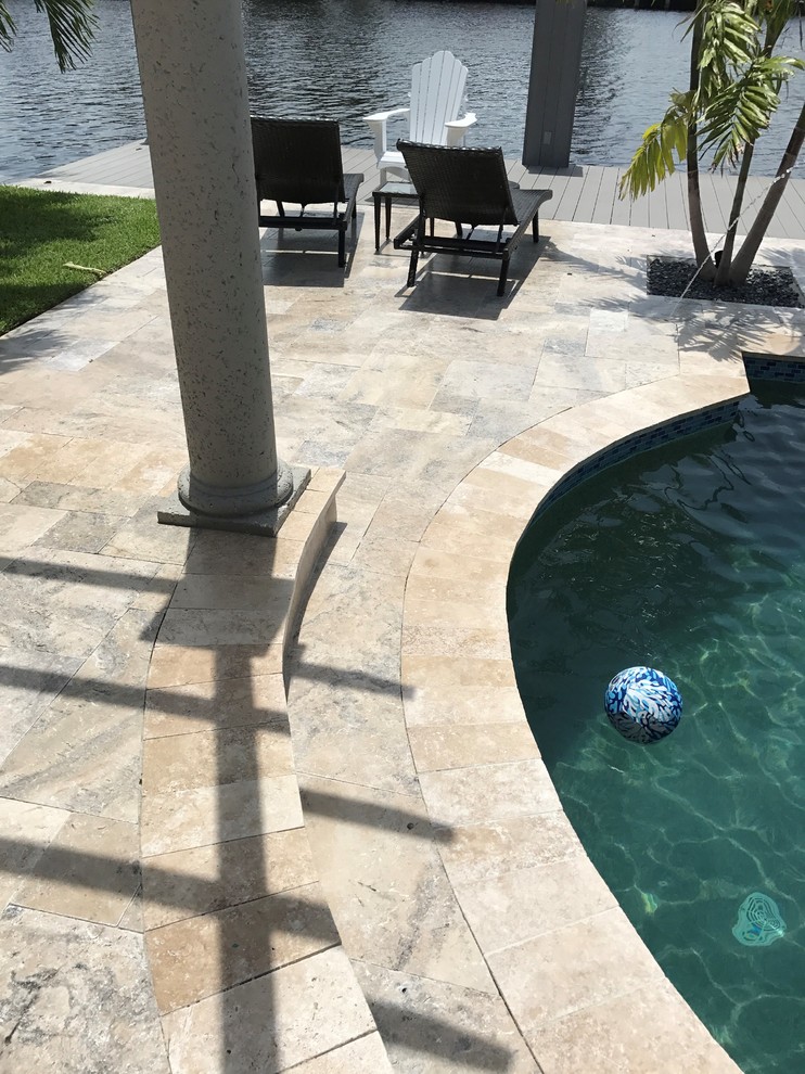 Diseño de piscina elevada contemporánea grande rectangular en patio trasero con adoquines de piedra natural
