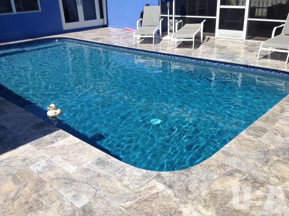 Imagen de piscina elevada moderna grande rectangular en patio trasero con adoquines de piedra natural