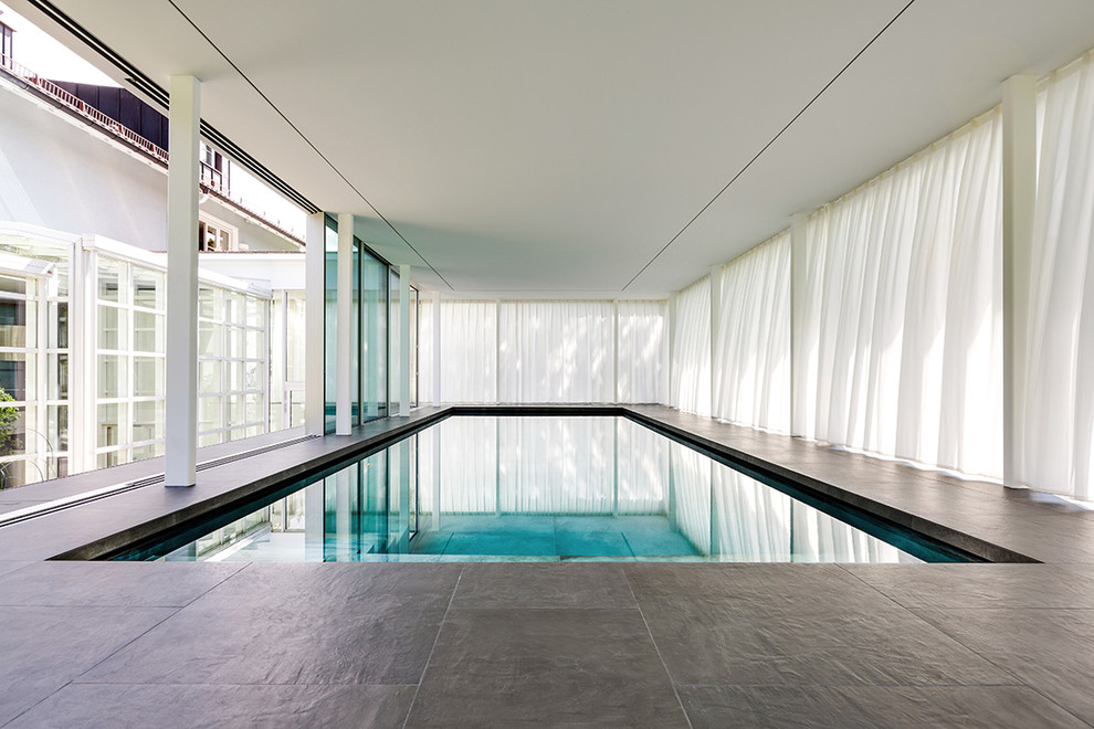 На фото: прямоугольный бассейн в доме в современном стиле с покрытием из каменной брусчатки с