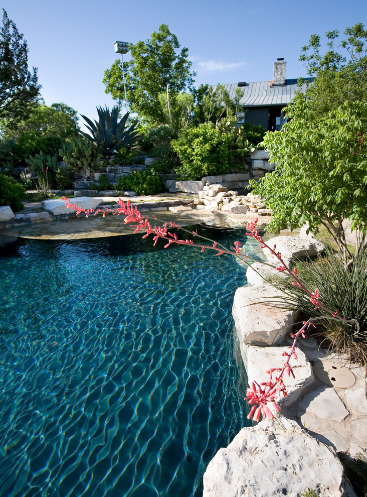 Medium sized farmhouse back custom shaped natural hot tub in Austin with natural stone paving.
