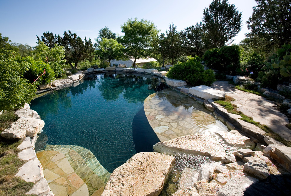 Example of a mid-sized farmhouse backyard stone and custom-shaped natural hot tub design in Austin