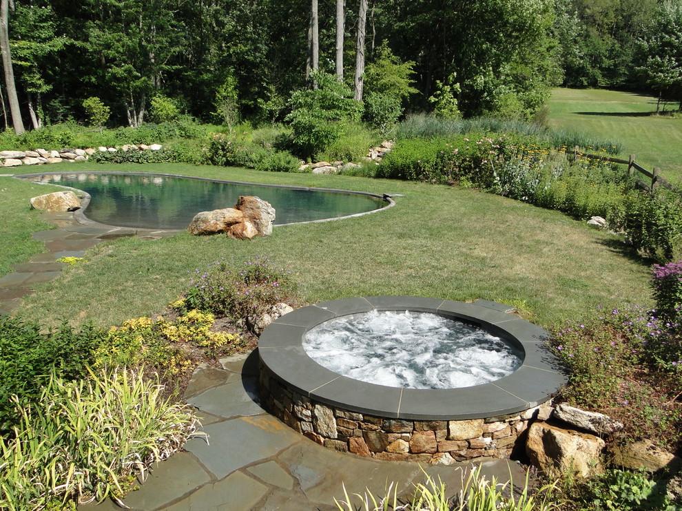 Foto de piscina natural clásica grande a medida en patio trasero con adoquines de piedra natural