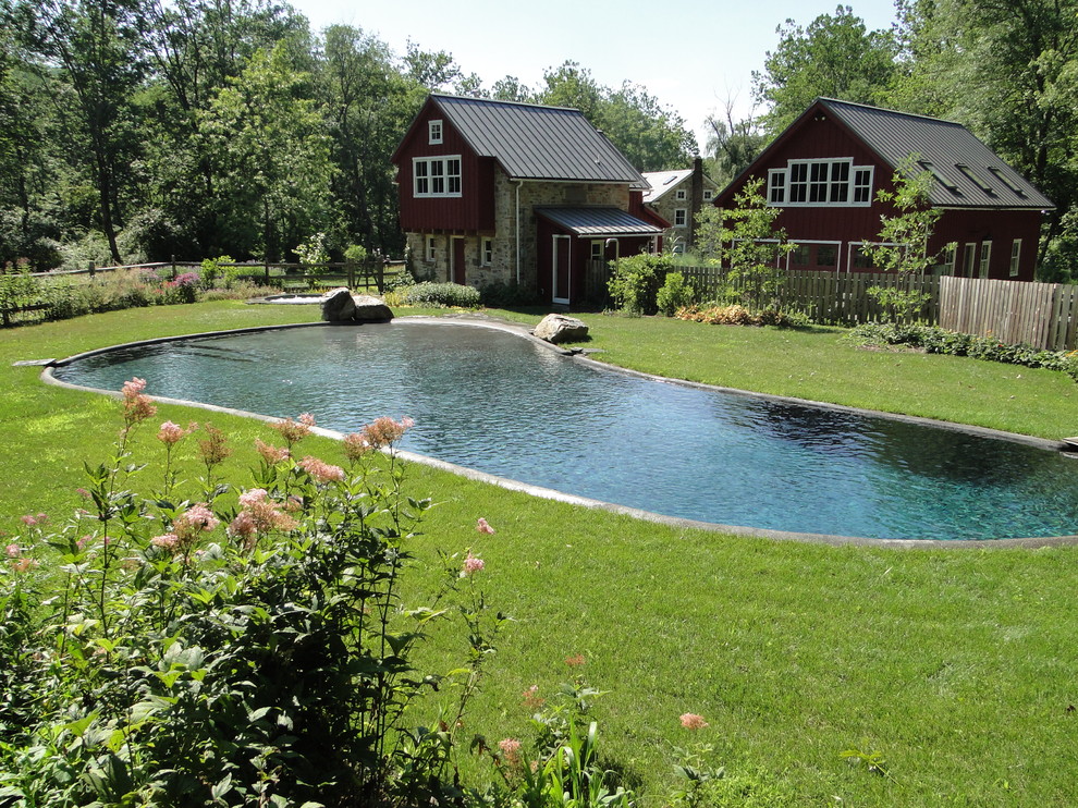 Ejemplo de piscina natural clásica grande a medida en patio trasero con adoquines de piedra natural