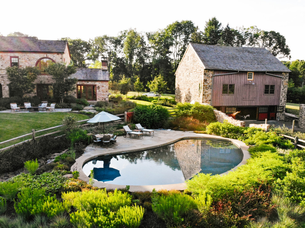 Свежая идея для дизайна: естественный бассейн среднего размера, в форме фасоли на заднем дворе в стиле рустика с домиком у бассейна и покрытием из каменной брусчатки - отличное фото интерьера