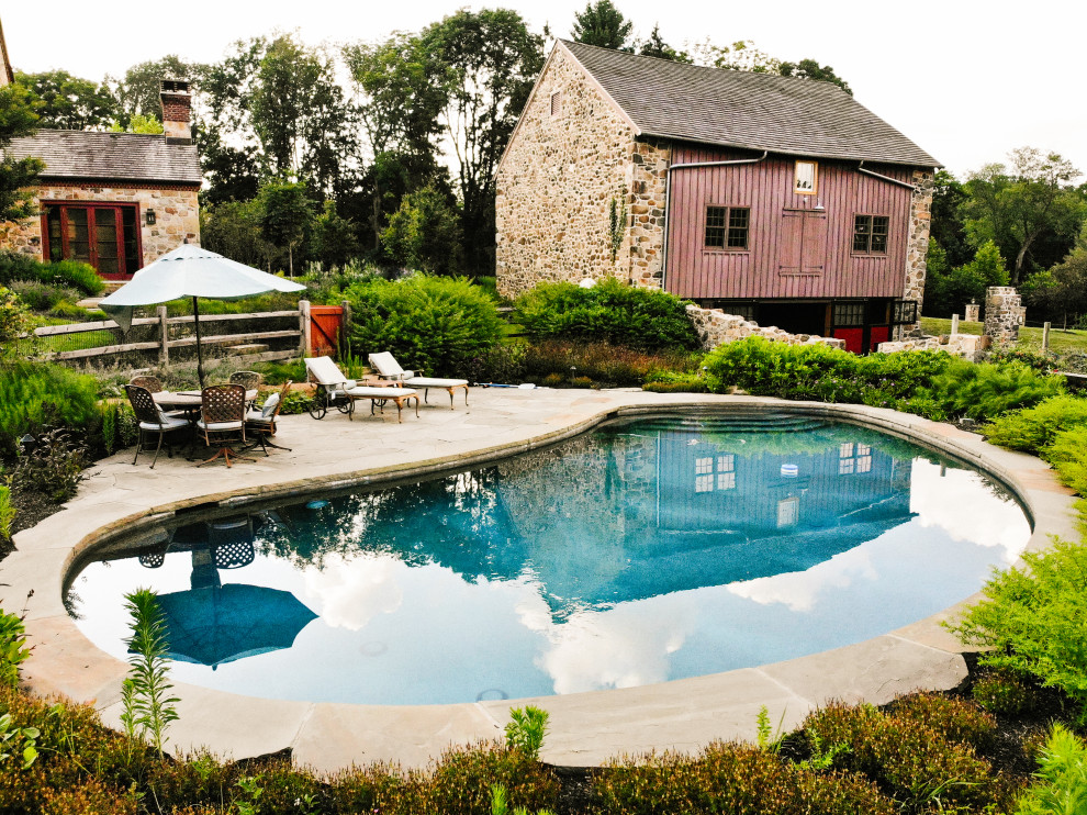 Immagine di una piscina naturale stile rurale a "C" di medie dimensioni e dietro casa con una dépendance a bordo piscina e pavimentazioni in pietra naturale