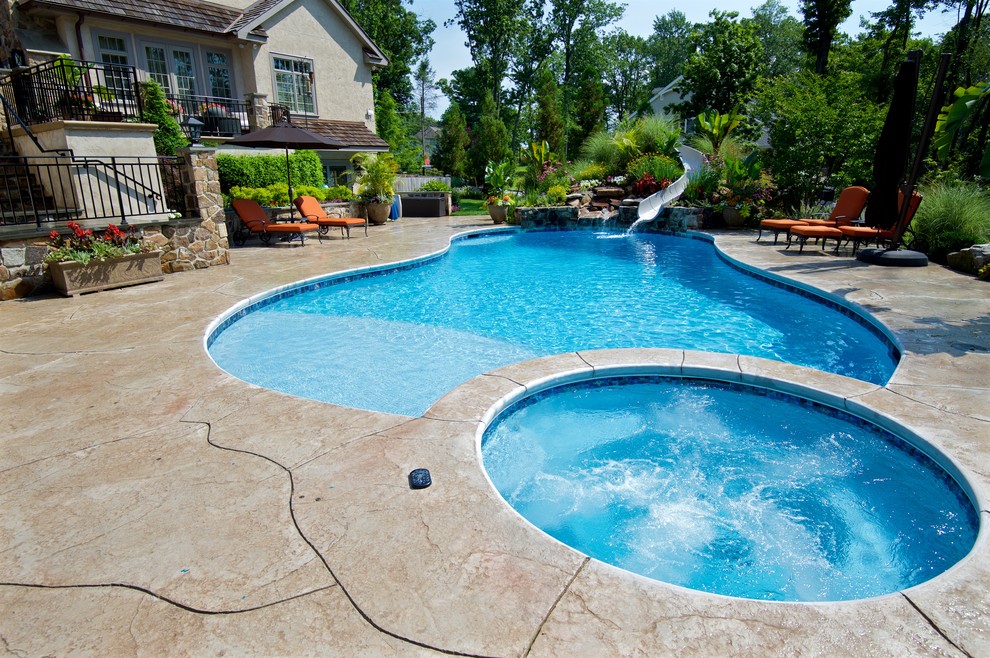 Foto de piscina con tobogán contemporánea grande a medida en patio trasero con suelo de hormigón estampado