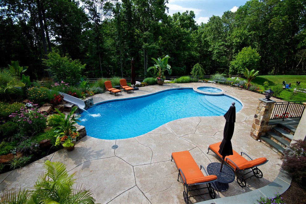 Diseño de piscina con tobogán contemporánea grande a medida en patio trasero con suelo de hormigón estampado