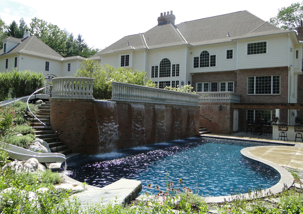 Esempio di una grande piscina design personalizzata dietro casa con fontane e pedane