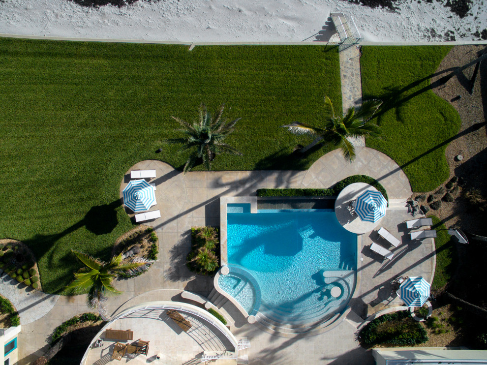 Diseño de piscina infinita actual a medida en patio trasero con adoquines de piedra natural