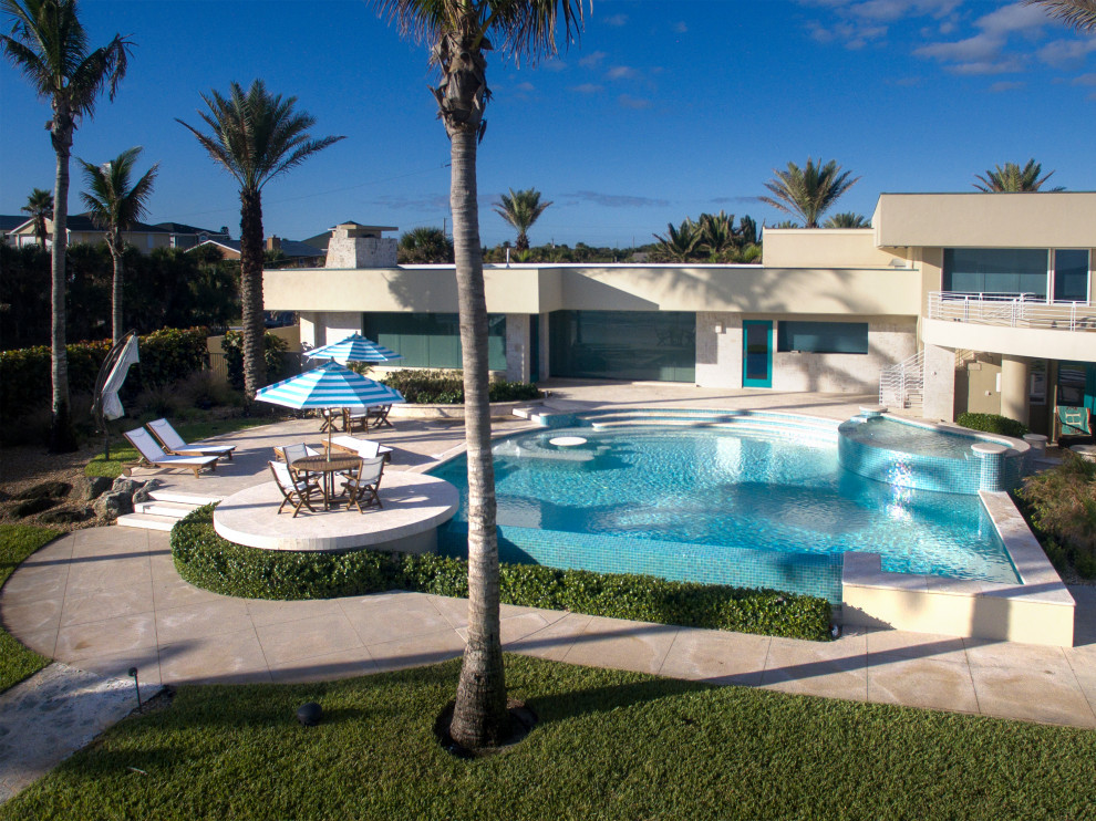 Photo of a contemporary back custom shaped infinity swimming pool in Orlando with natural stone paving.