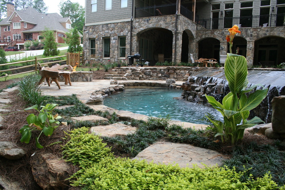 Modelo de piscina con tobogán exótica grande a medida en patio trasero con adoquines de piedra natural