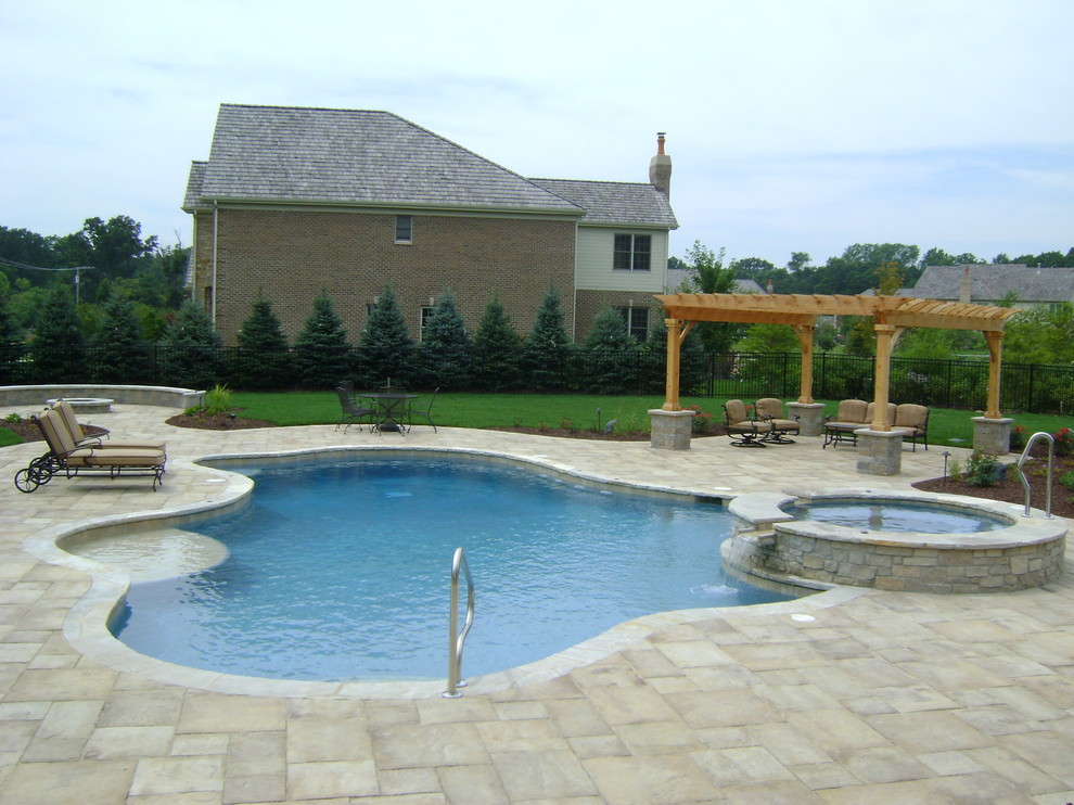 Esempio di una piscina naturale tradizionale personalizzata di medie dimensioni e dietro casa con una vasca idromassaggio e pavimentazioni in cemento