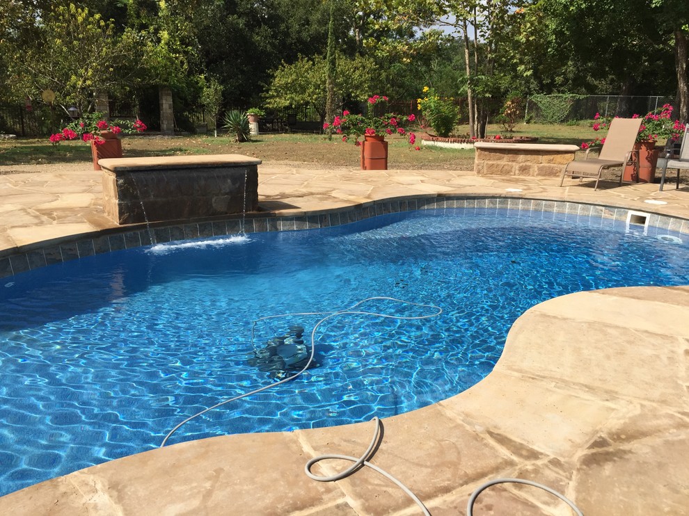 Esempio di una grande piscina naturale moderna personalizzata dietro casa con fontane e pavimentazioni in pietra naturale