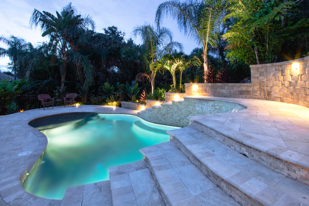 Cette photo montre un piscine avec aménagement paysager arrière exotique sur mesure avec des pavés en pierre naturelle.