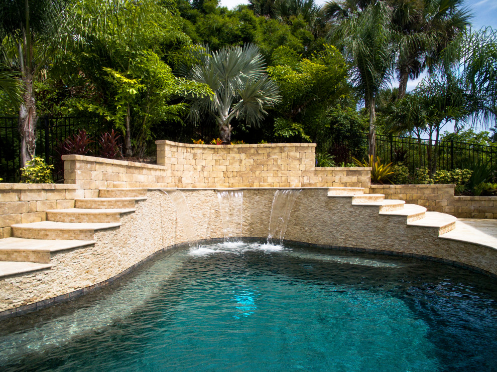 Exemple d'un piscine avec aménagement paysager arrière exotique sur mesure avec des pavés en pierre naturelle.