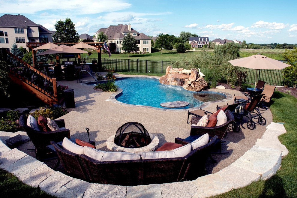 This is an example of a medium sized back custom shaped natural swimming pool in Orlando with a water feature and natural stone paving.