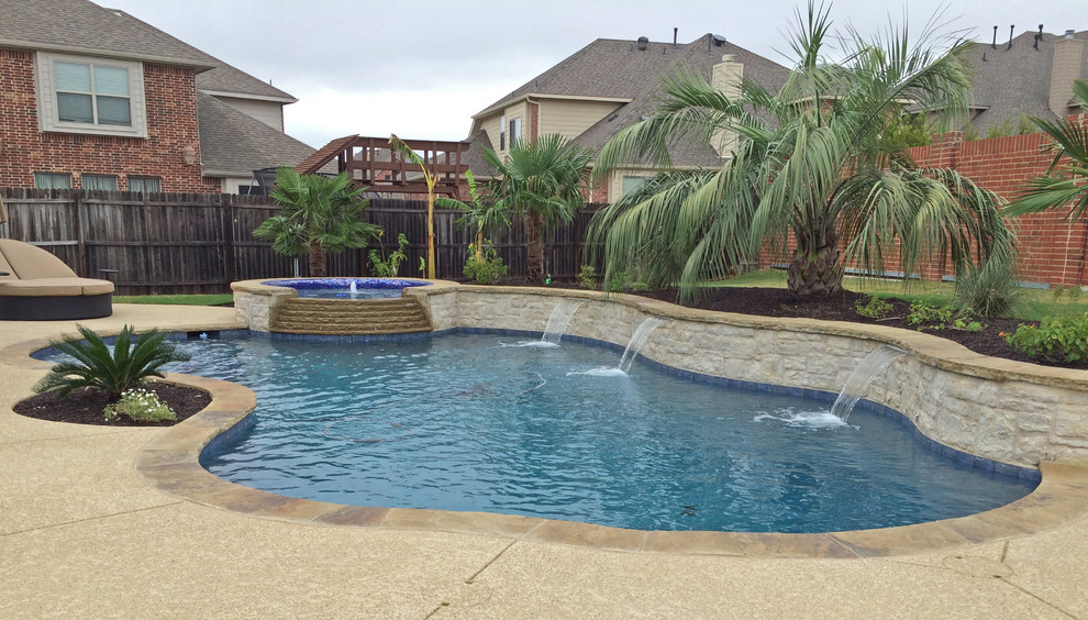 На фото: естественный бассейн среднего размера, произвольной формы на заднем дворе в морском стиле с джакузи и покрытием из бетонных плит