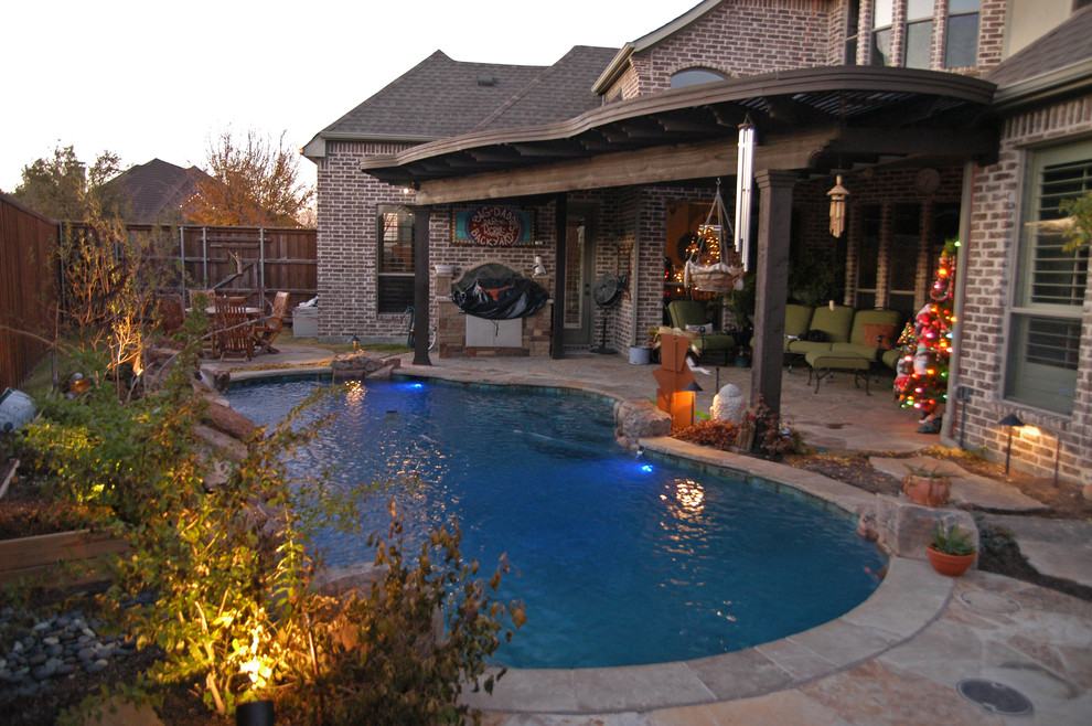 На фото: естественный бассейн среднего размера, произвольной формы на заднем дворе в стиле фьюжн с джакузи и покрытием из каменной брусчатки