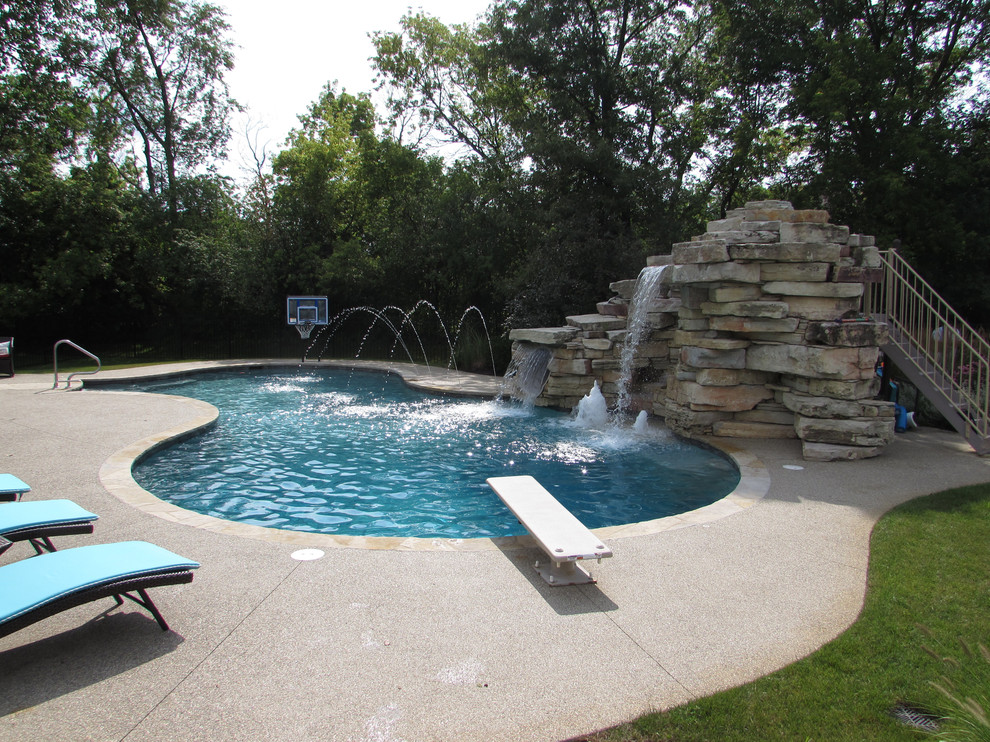 Diseño de piscina con tobogán actual de tamaño medio a medida en patio trasero con suelo de hormigón estampado