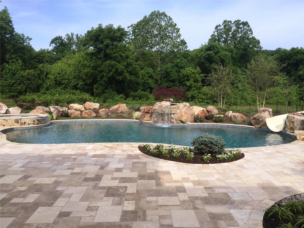 Idée de décoration pour une piscine naturelle et arrière sur mesure avec un toboggan et des pavés en pierre naturelle.