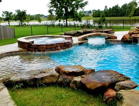 Aménagement d'une grande piscine arrière moderne sur mesure avec un point d'eau et du béton estampé.