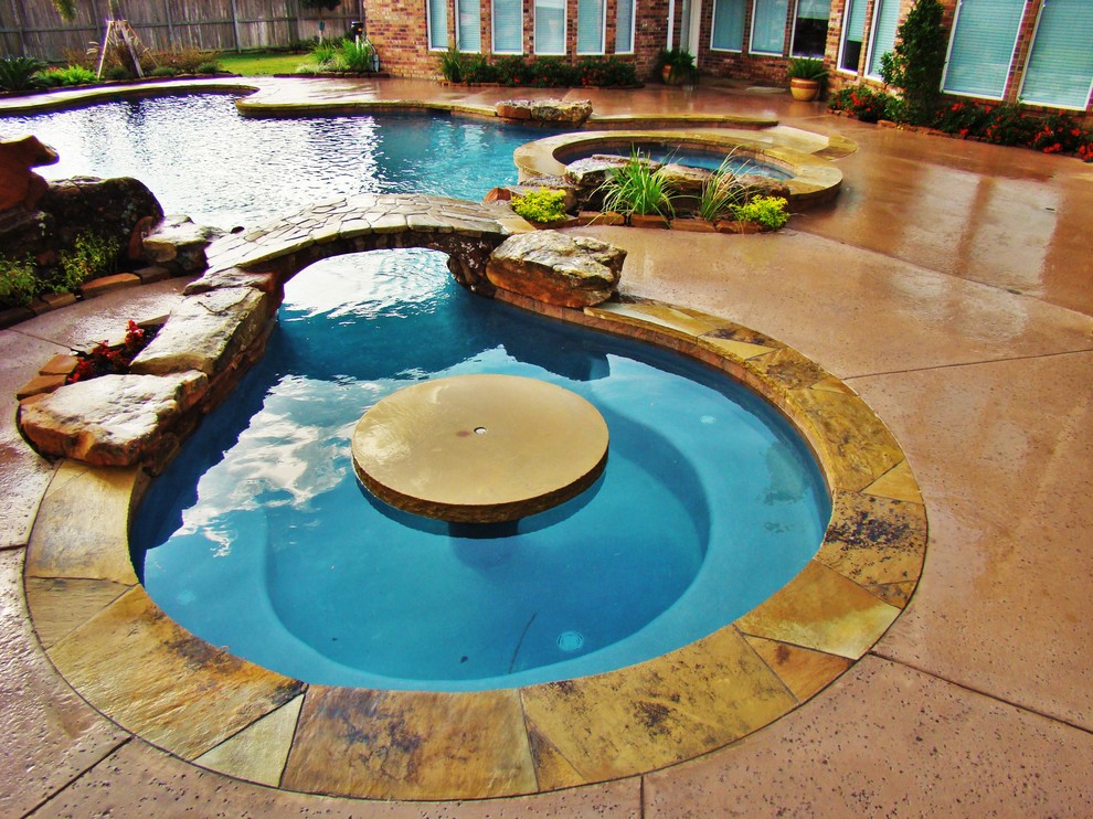 Diseño de piscina con fuente minimalista grande a medida en patio trasero con suelo de hormigón estampado