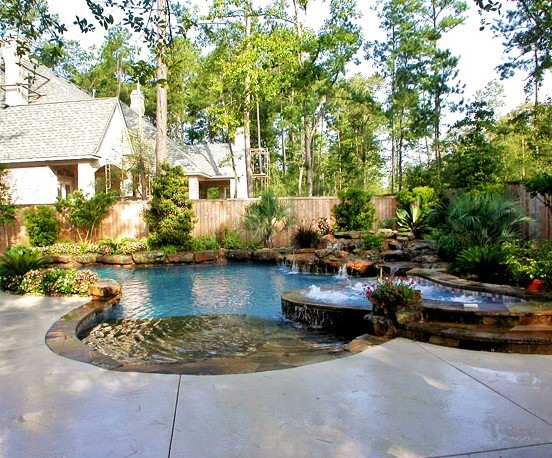Diseño de piscina con fuente moderna grande a medida en patio trasero con suelo de hormigón estampado