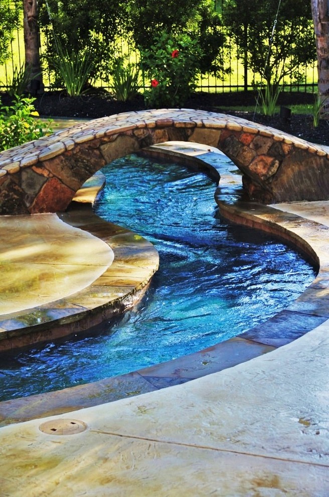 Réalisation d'une grande piscine arrière minimaliste sur mesure avec un point d'eau et du béton estampé.