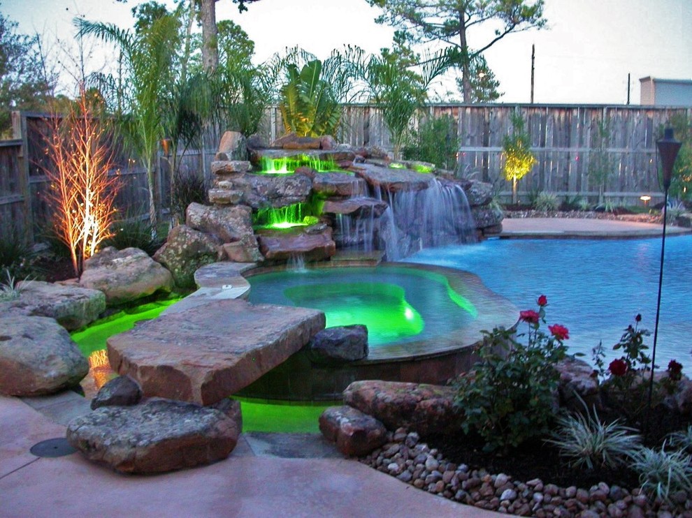 Large minimalist backyard stamped concrete and custom-shaped pool fountain photo in Houston