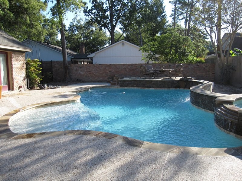 Exempel på en klassisk anpassad pool på baksidan av huset, med granitkomposit