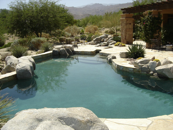 Idee per una piscina naturale mediterranea personalizzata di medie dimensioni e dietro casa con pavimentazioni in pietra naturale e una vasca idromassaggio