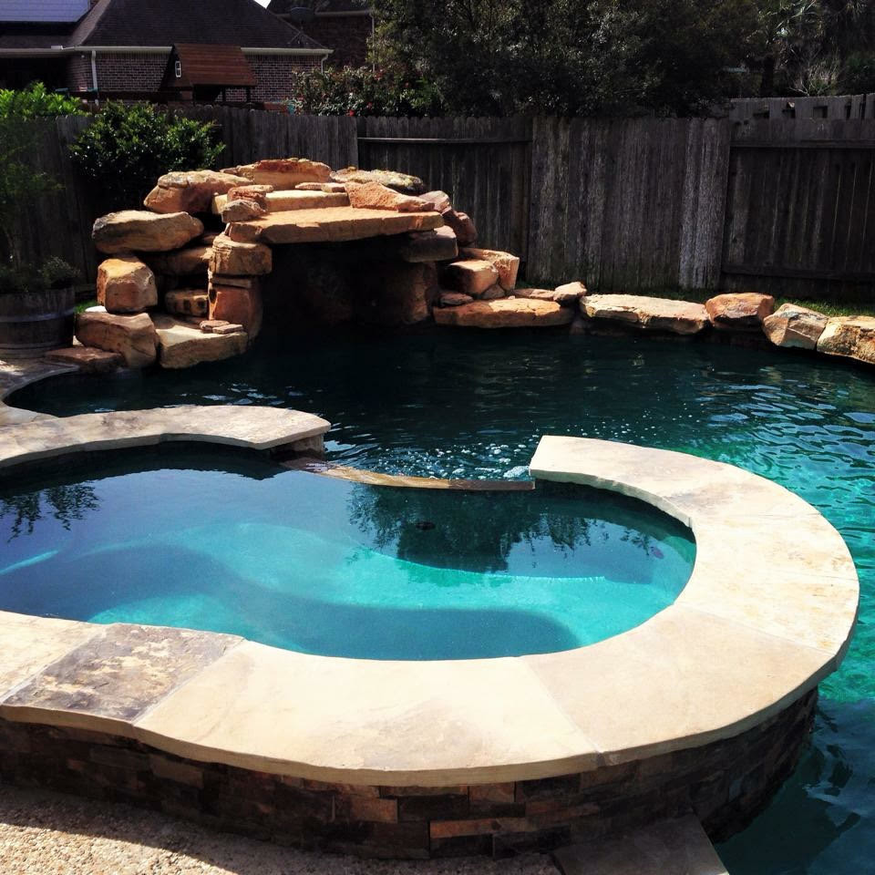Ispirazione per una piscina monocorsia american style a "C" di medie dimensioni e dietro casa con una vasca idromassaggio e pavimentazioni in pietra naturale