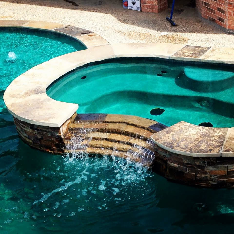 Immagine di una grande piscina monocorsia classica a "C" dietro casa con una vasca idromassaggio e pavimentazioni in pietra naturale