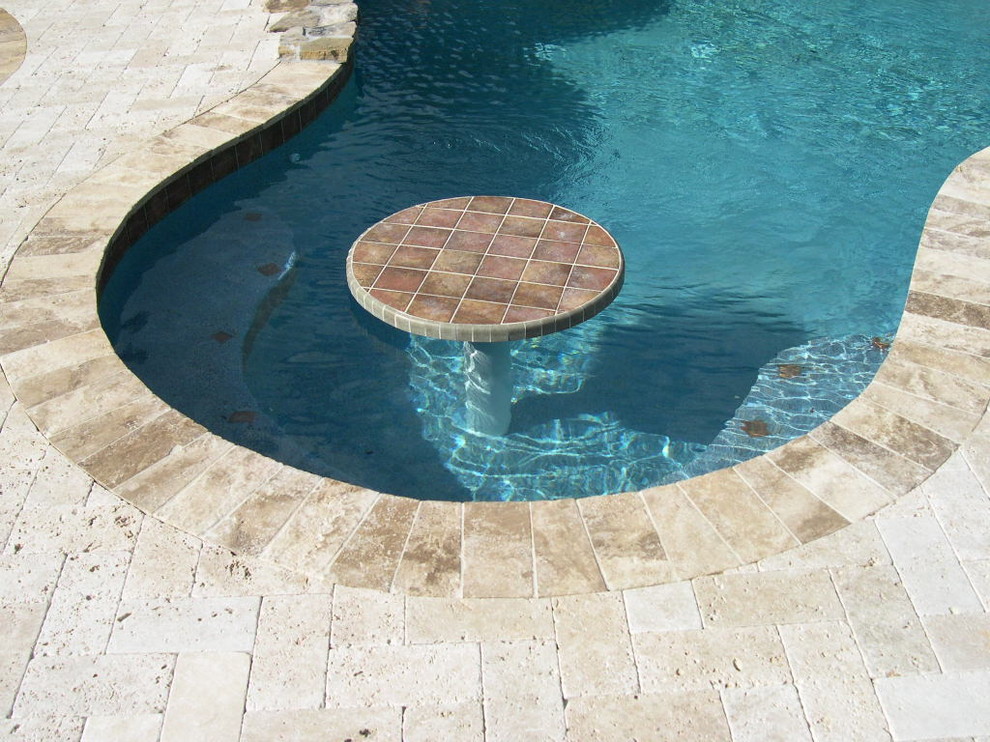 Example of an island style backyard brick and custom-shaped pool design in Miami