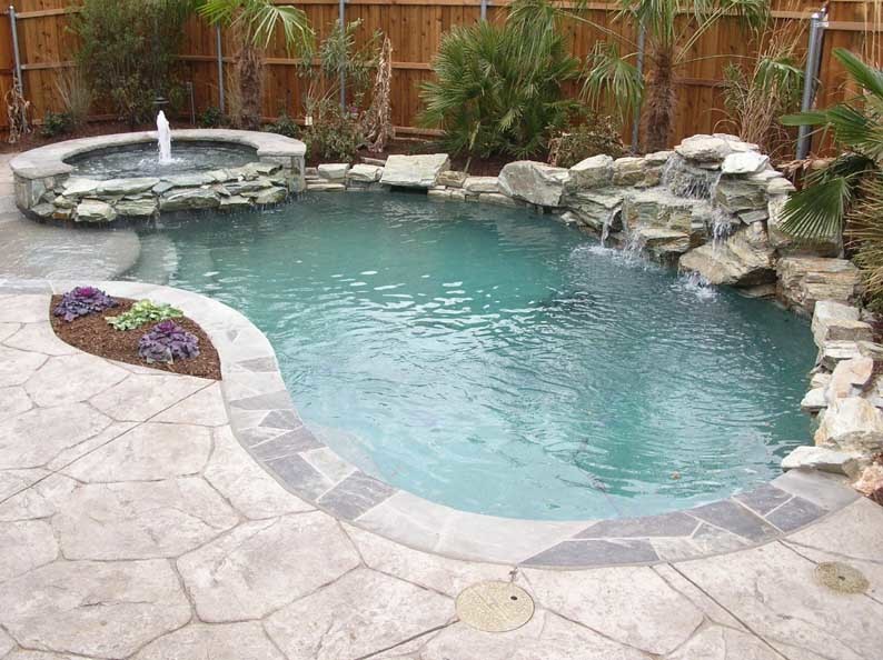 Klassisk inredning av en liten anpassad pool på baksidan av huset, med spabad och naturstensplattor