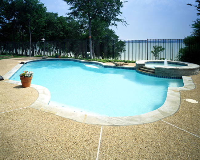 Ispirazione per una piscina tradizionale personalizzata di medie dimensioni e dietro casa con una vasca idromassaggio e lastre di cemento
