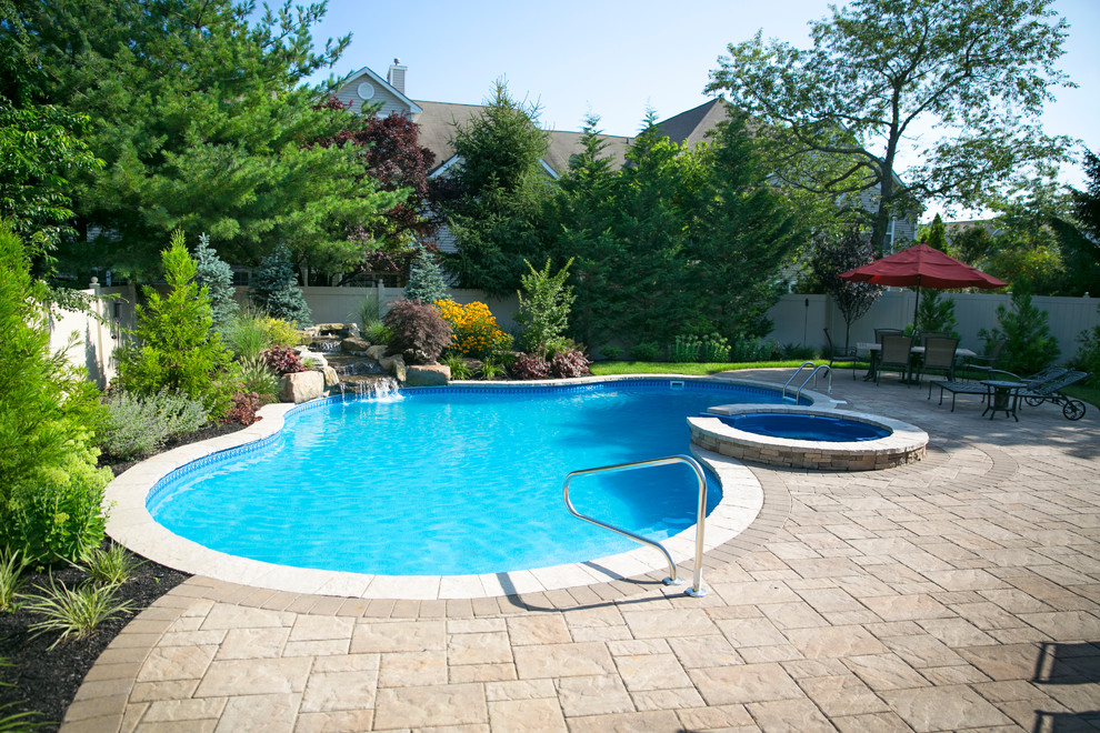 Стильный дизайн: бассейн среднего размера, произвольной формы на заднем дворе в стиле фьюжн с джакузи и мощением тротуарной плиткой - последний тренд