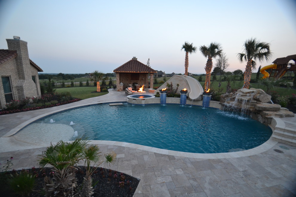 Modelo de piscina con tobogán exótica de tamaño medio a medida en patio trasero con adoquines de hormigón