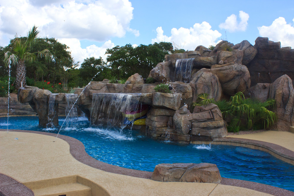Foto di un'ampia piscina naturale costiera personalizzata dietro casa con un acquascivolo e pedane