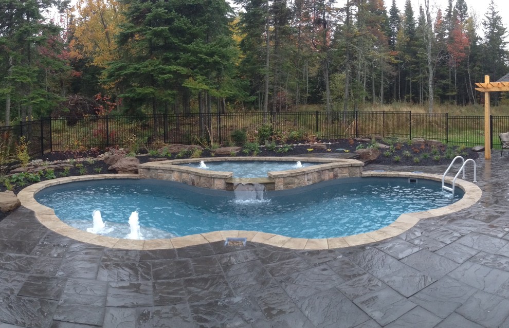 Exempel på en mellanstor klassisk pool på baksidan av huset, med naturstensplattor