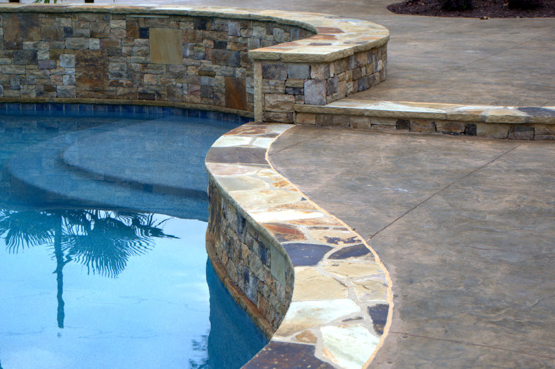 Idéer för en stor klassisk pool på baksidan av huset, med poolhus och stämplad betong