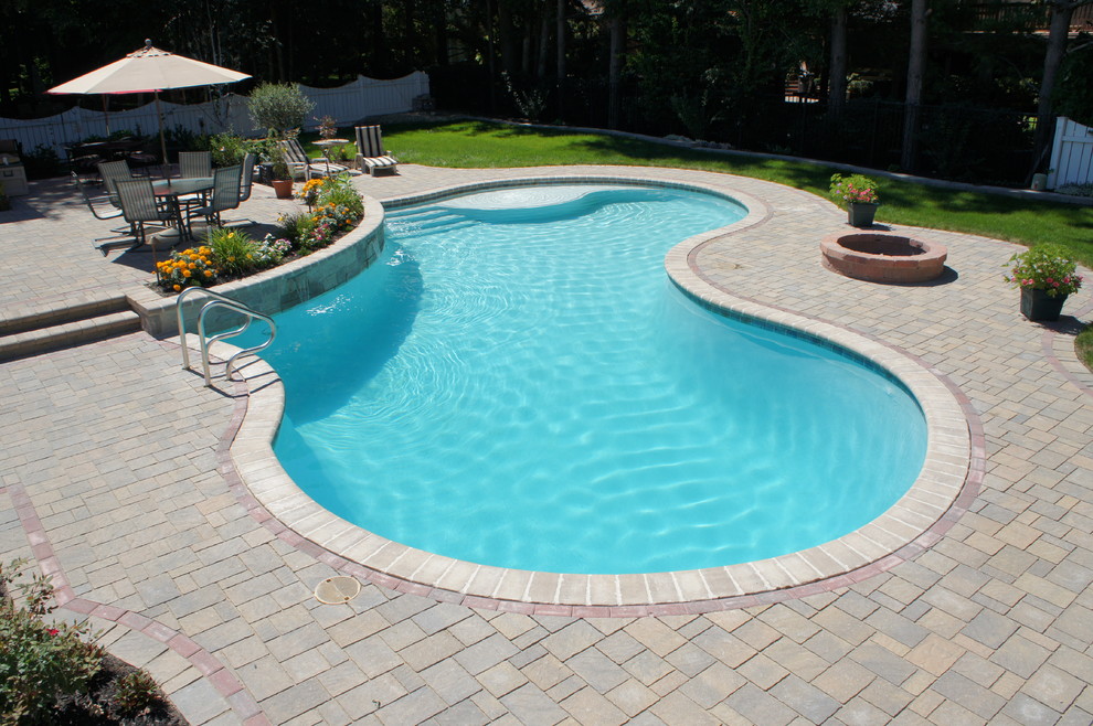 Esempio di una piscina naturale classica a "C" di medie dimensioni e dietro casa con fontane e pavimentazioni in cemento