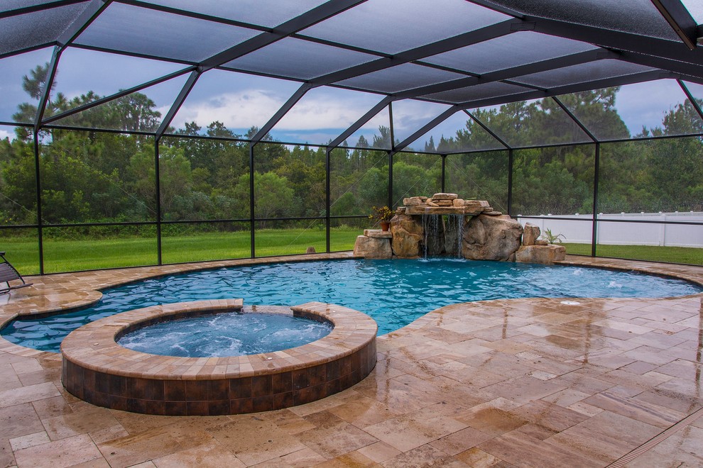 Inspiration for a large world-inspired back custom shaped natural swimming pool in Tampa with a water feature and natural stone paving.