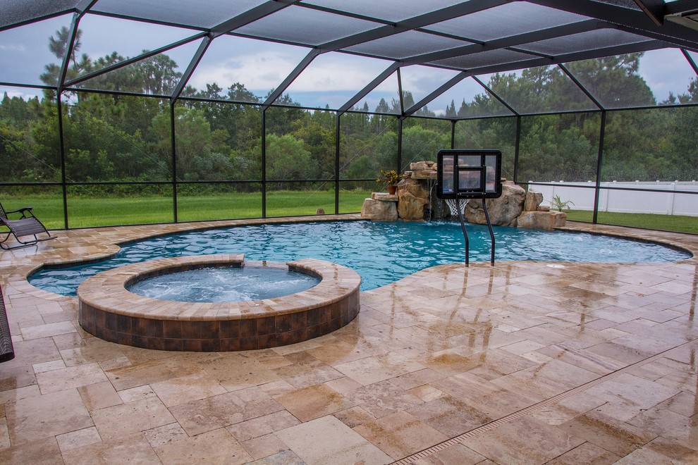 Ejemplo de piscina con fuente natural exótica grande a medida en patio trasero con adoquines de piedra natural