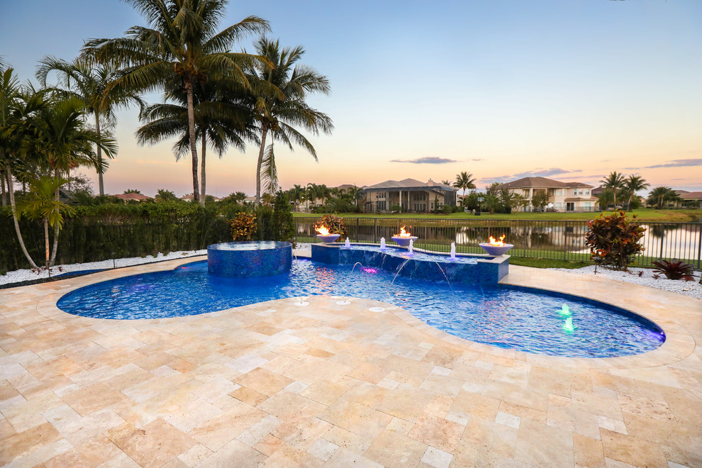 Foto de piscina natural tropical grande a medida en patio trasero con adoquines de piedra natural