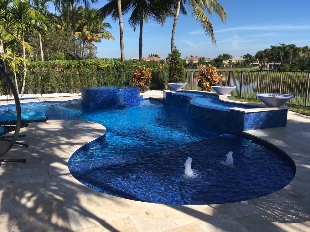 Diseño de piscina natural tropical grande a medida en patio trasero con adoquines de piedra natural