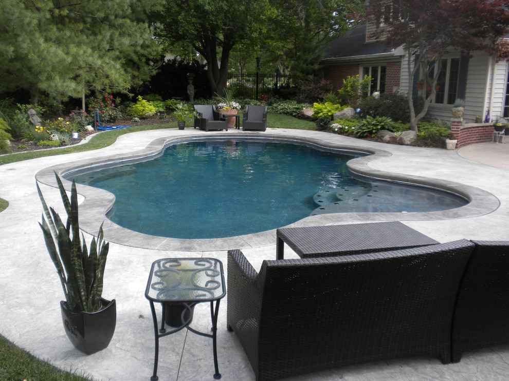 Diseño de piscina tradicional de tamaño medio a medida en patio trasero con suelo de hormigón estampado