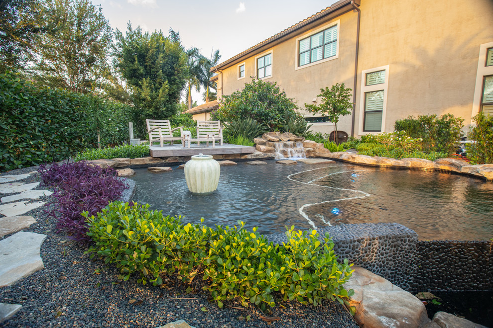Immagine di una piscina naturale personalizzata di medie dimensioni e dietro casa con una vasca idromassaggio e ghiaia