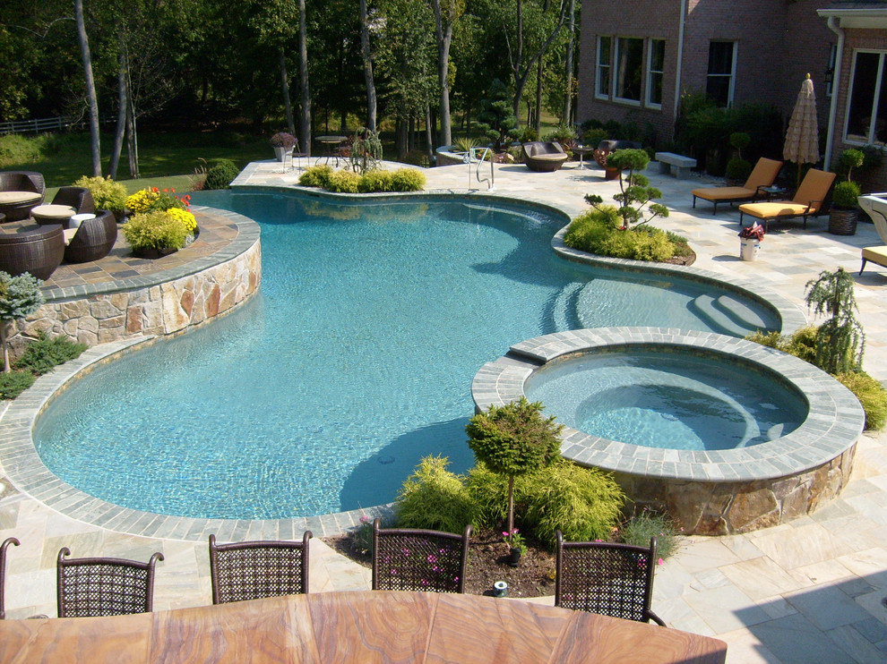 Immagine di una grande piscina tradizionale personalizzata dietro casa con una vasca idromassaggio e piastrelle